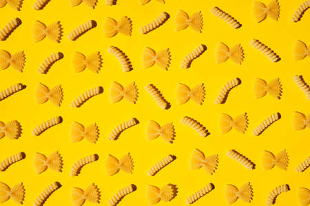 Uncooked curly pasta pattern on yellow background. Traditional dry raw macaroni pattern. Nobodyの写真素材