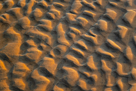 Abstract view of natural sand dune formation at the beach. Curly sand wave pattern closeup....