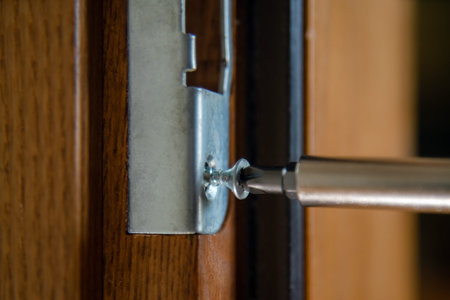 Close up of carpenter repairing door lock. Installing a door handle. Handyman tightening door hinge...