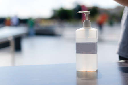 Hand sanitizer gel in public. Antibacterial lotion bottle outside. Close up view of antiseptic in the street.の写真素材