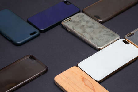 Pile of multicolored plastic back covers for mobile phone. Choice of smart phone protector case accessories background. Silicone phone backs on black backgroundの写真素材