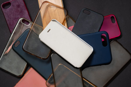 Pile of multicolored plastic back covers for mobile phones on black background