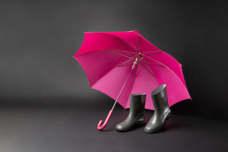 Rubber shoes and umbrella isolated on black background. Rain season and weather forecast. Nobodyの写真素材
