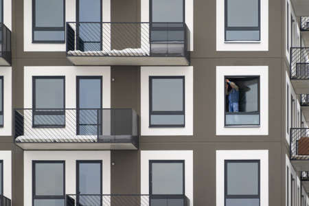 Carpenter installing a window high up in an apartment block. Contractor fixing a glass window.の写真素材