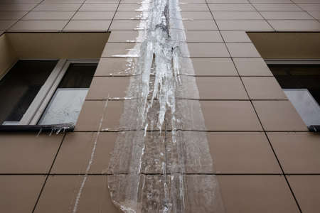 Frozen rain pipe on an apartment building. Ice on the building wall.の写真素材