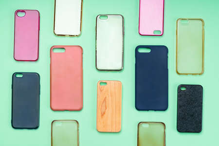 Pile of multicolored plastic back covers for mobile phone. Choice of smart phone protector accessories on green background. A lot of silicone phone backs or skins next to each otherの写真素材