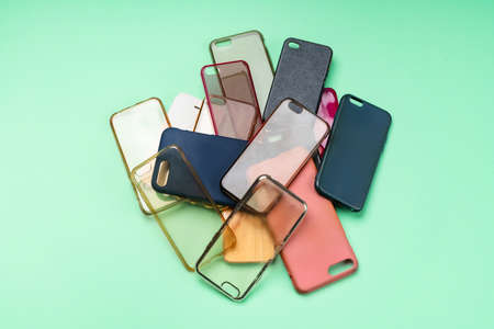 Pile of multicolored plastic back covers for mobile phones on green backgroundの写真素材