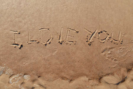 I love you sign whiten on the sand at the beach. Romantic love symbol at tropical seashore at sunset.の写真素材