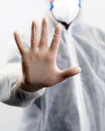 Doctor with full body suit and mask showing stop sign with his hand on white background.の写真素材