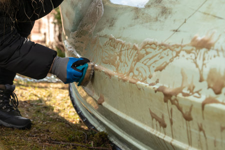 Close up of hand with gloves scrubbing dirt of the boat surface outside. Sailboat maintenance.