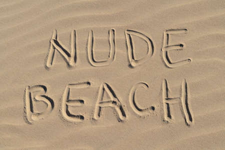 Nude beach letters written on the sand at the beach on a sunny day. Naked sunbathing. Naturalist lifestyle.の写真素材
