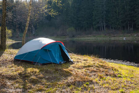 Camping tent set up near the lake in the forest. Relaxing in a camp site outdoors.の写真素材