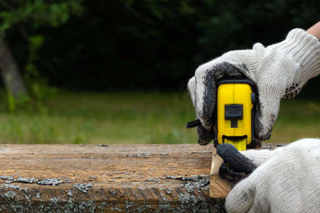 Close up of carpenter hand wearing working gloves and measuring plank with a tape measure.の写真素材