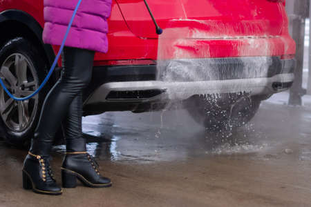 Close up of woman washing the car with high pressure water at self service car wash.の写真素材