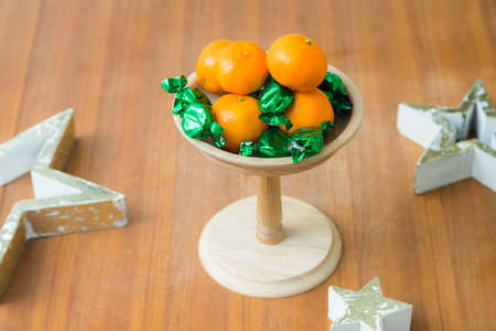 Christmas or birthday themed wooden tray stand with sweets and tangerines on the tableの写真素材