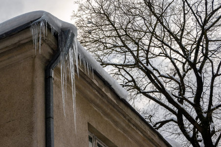Sharp icicles hanging on the edge of the roof. Melting snow forms icicle.