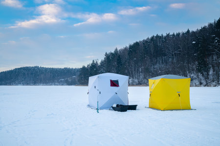 Ice fishing tent on a frozen lake at sunset. Fisherman camp on a peaceful winter evening.の写真素材