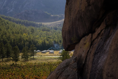 Tiny houses surrounded by trees on the ridge of the mountain. Small ger huts on the crest of the hill on a sunny day.の写真素材