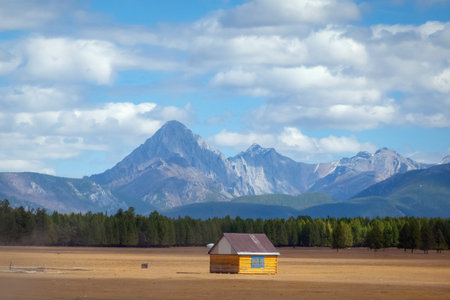 House in the countryside with the mountains in the background. Farm cabin in the rural country surrounded by forest and hills with the snowy tops.の写真素材