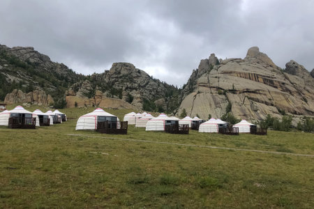 Yurt camp surrounded by trees on the ridge of the mountain. Small ger huts on the crest of the hill on a cloudy day.の写真素材