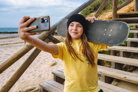 Teenager girl with skateboard listening to music on headphones. Outdoors.の写真素材