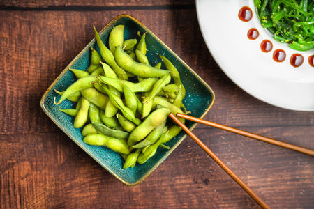 edamamen Green soybeans on a plate with chopsticks on a wooden tableの写真素材