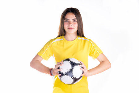 Portrait of a beautiful girl in a yellow t-shirt with a soccer ball on a white backgroundの写真素材