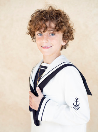 Positive religious communion boy with book standing on pink backgroundの写真素材