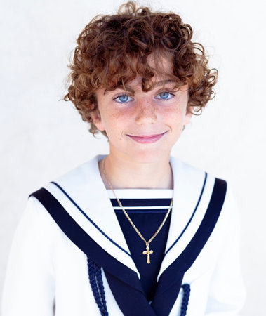 Positive religious communion boy with book standing on pink backgroundの写真素材