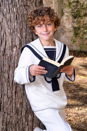 Portrait of a young boy reading a book in the park.