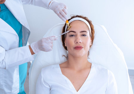 Crop beautician with face massager of client in aesthetic clinicの写真素材