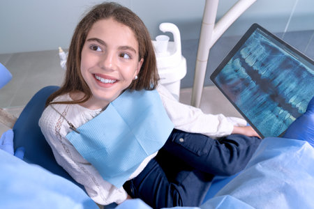 girl with opened mouth teeth treatment in dentist clinic with tablet smilingの写真素材