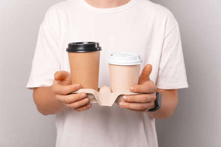 Closeup photo of a mans hands holding two cups of paperの写真素材