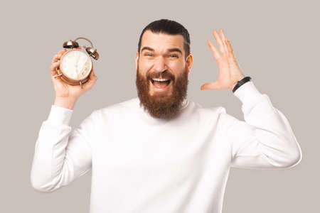 A photo of an excited man holding a clockの写真素材