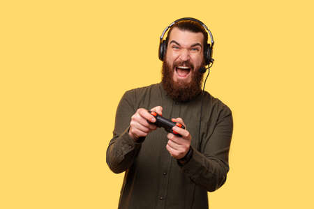 A picture of a young bearded gamer playing with a consoleの写真素材