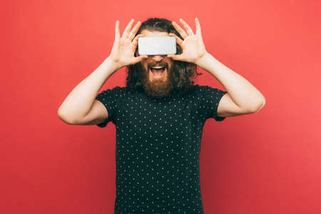 A photo of a man holding a phone above his eyesの写真素材