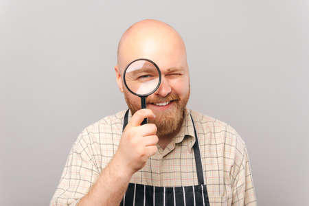 A photo of a young barista looking through a magnifying glassの写真素材
