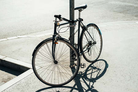 A photo of a bicycle leaning against a pole outsideの写真素材