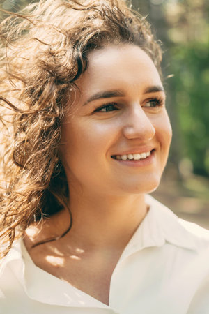Close up portrait of young curly woman looking away outdoor