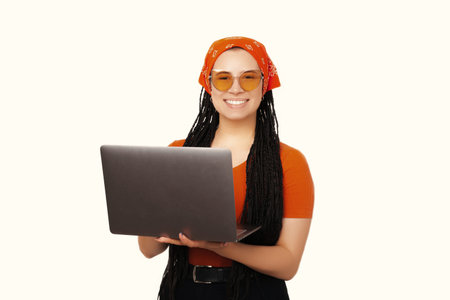Happy young woman with box braids using laptop and looking at the camera.