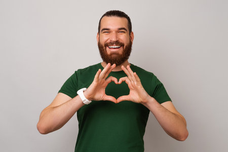 Young smiling man made a heart shape with fingers for love and charity.の写真素材