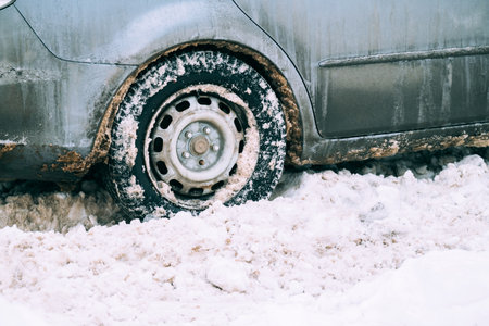 Close up shot of an old green car tire full of dirty and white snow in winter.の写真素材