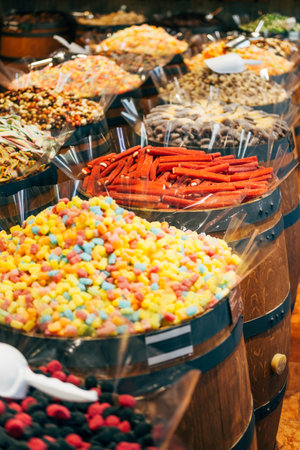 Vertical shot of a some big barrels full of colourful sweets in a market.