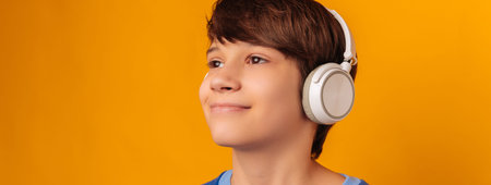Banner size cropped photo of a smiling teen boy wearing wireless headphones.
