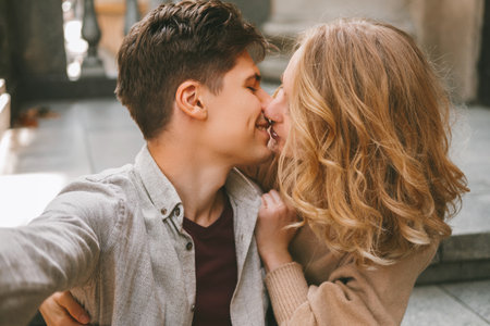 Young cheerful couple is taking a selfie while giving a kiss to each other.の写真素材