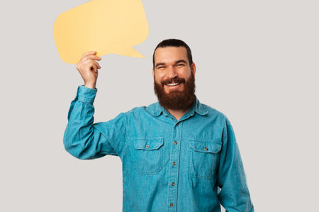 Handsome smiling man is holding a yellow bubble speech above his head.