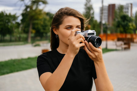 Young blonde woman practices her new hobby outdoors with a vintage camera.の写真素材
