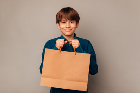 Cheerful teen boy is holding tight a clean shopping bag with copy space.の写真素材
