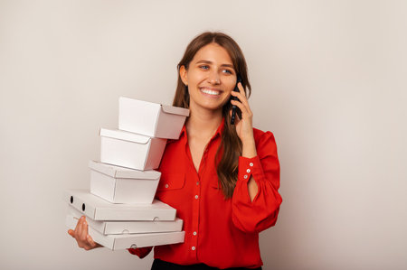 Confident wide smiling woman talking on the phone is holding some lunch boxes.の写真素材