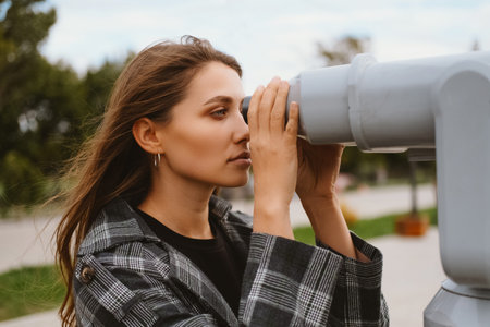 Gorgeous blonde woman is looking at a wonderful view through city binoculars.